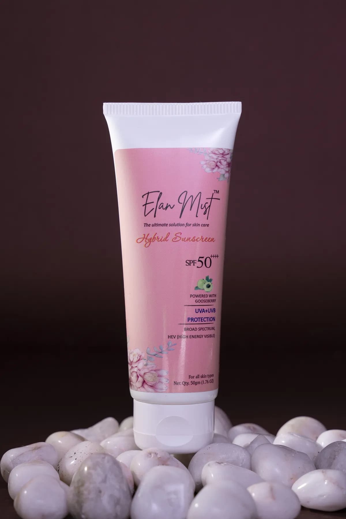 Close-up of Elanmist Hybrid Sunscreen tube resting on smooth white stones